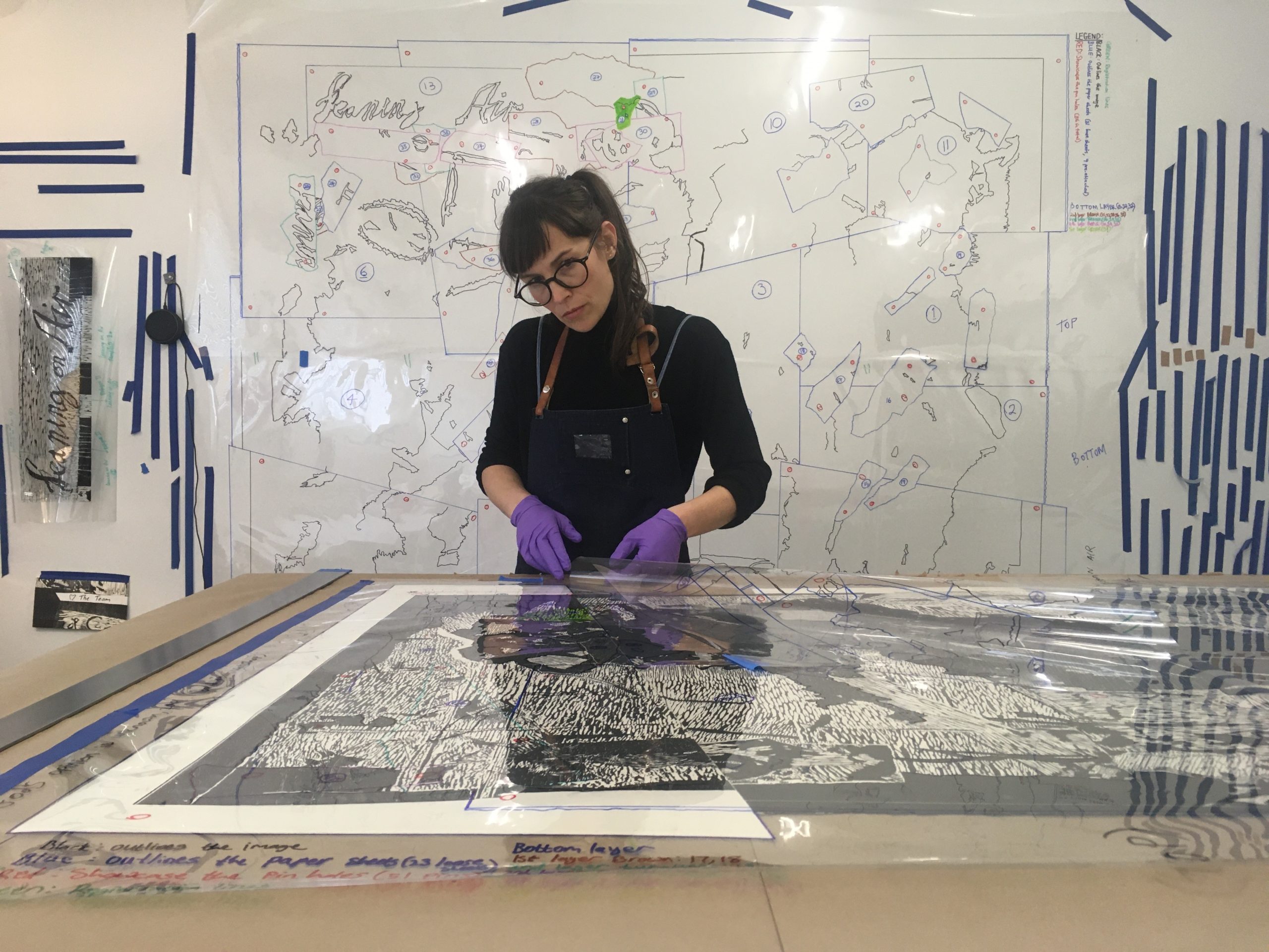 Jillian Ross stands at a large table with a print laid out on top of it.